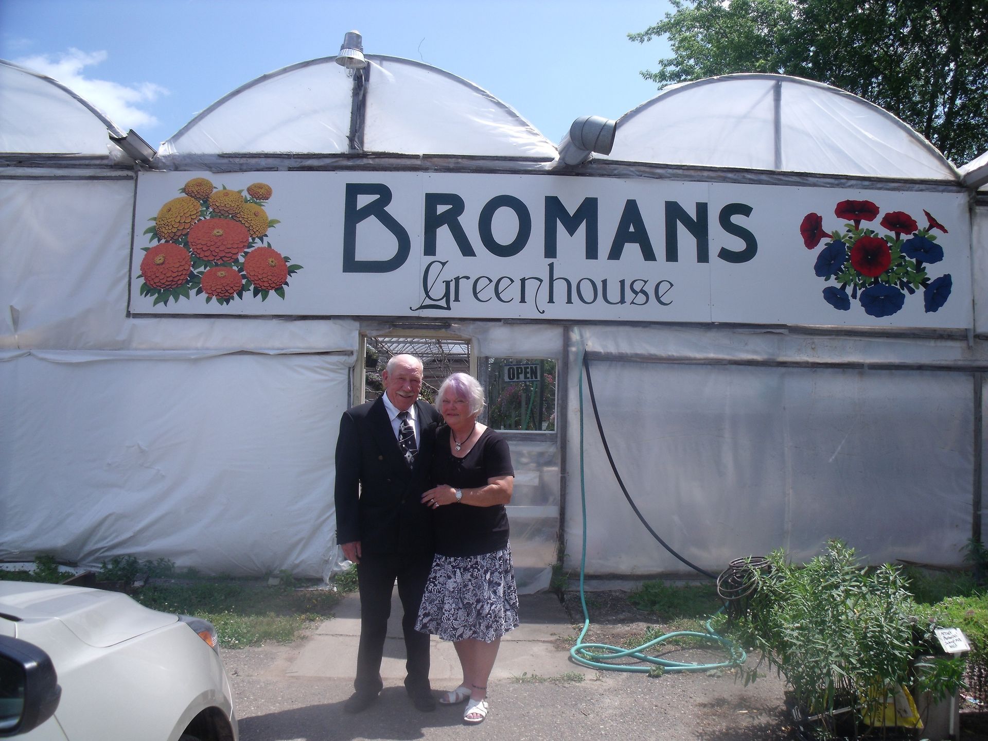 a man and woman standing in front of a Broman's greenhouse