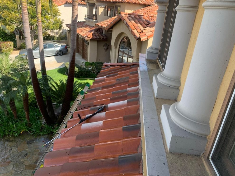 Roof tiles and porch columns overlooking a landscaped driveway and neighboring house