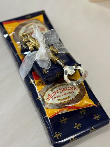A wrapped dark blue and gold chocolate bar tied with a silver ribbon and attached decorative keychain.