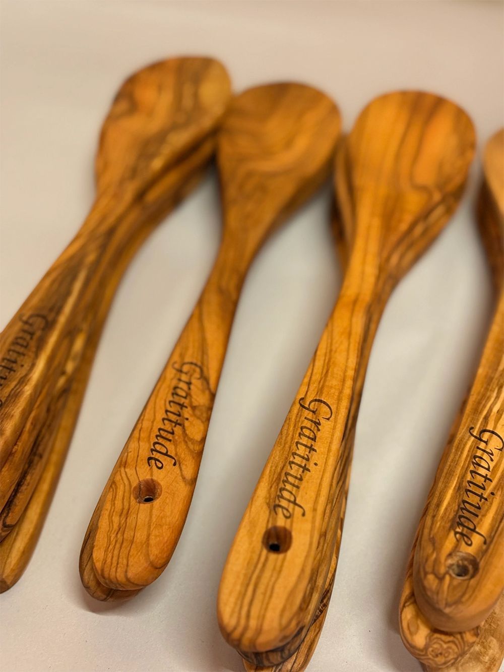 Four wooden spoons with carved handles laid side by side on a light surface.