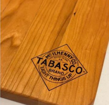 TABASCO brand logo burned into a light wooden surface.