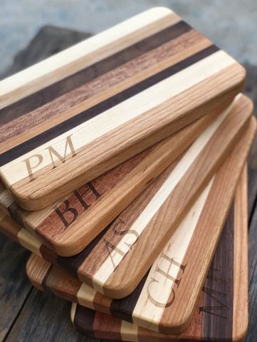 Stacked wooden cutting boards with engraved initials on a table.
