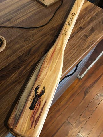 Wooden baseball bat with a painted praying mantis on a wood floor