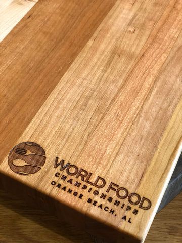 Wooden cutting board engraved with the World Food Championships logo and brand mark.