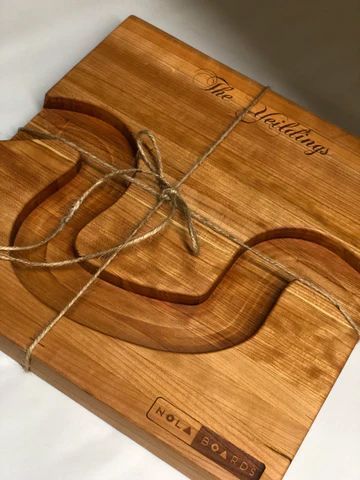 Wooden board with engraved line art and a clear eyeglass frame laid on top.