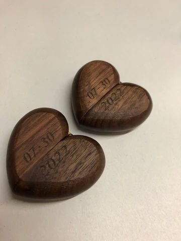 Two carved wooden heart-shaped objects with engraved text on a light surface.