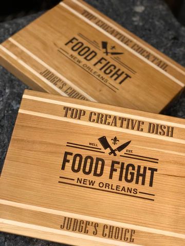 Two wooden 'Food Fight New Orleans' award plaques with 'Top Creative' and 'Judge’s Choice' text.