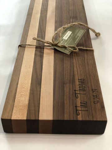 Wooden cutting board with striped end-grain design and a twine-tied tag on top