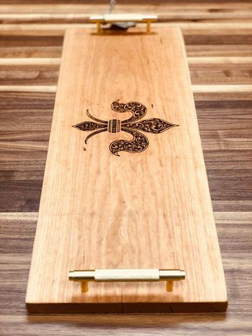 Wooden paddle board with a carved decorative symbol and brass handle
