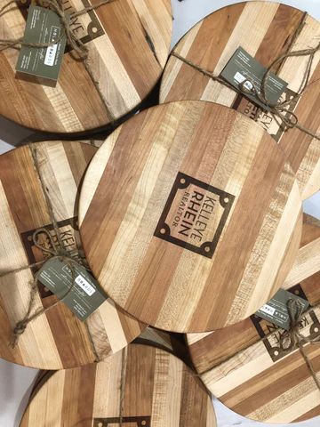 Round wooden 'PURINA PINK' tables with tags, stacked or displayed in a store setting.