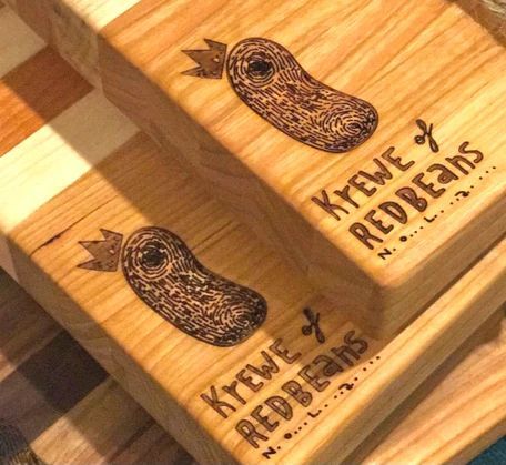 Wooden cutting boards engraved with a peanut and the words 'KREVÉ REDBEANS' on a wood surface