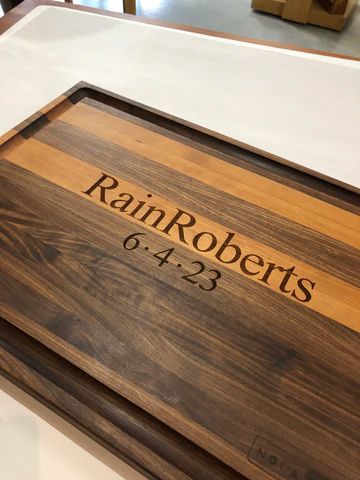 Wooden cutting board engraved with 'Rain Roberts' and the date 6-4-23