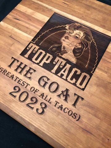 Wooden sign reading 'Top Taco, The Goat of All Tacos 2023' with a goat illustration.