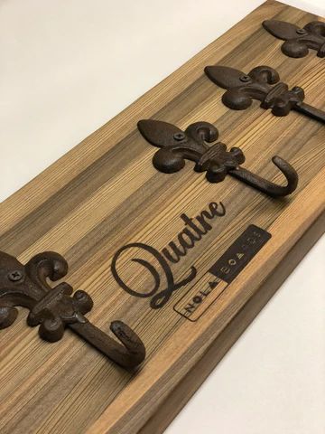 Wooden wall-mounted coat rack with black hooks and a custom 'Quail' nameplate