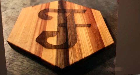 Wooden hexagonal plaque with a dark engraved symbol on a dark tabletop
