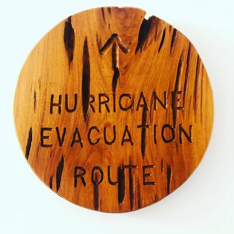 Wooden sign reading 'HURRICANE EVACUATION ROUTE' with an upward arrow in black paint.