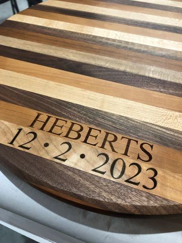 Striped wooden cutting board engraved 'HEBERTS 12-2-2023'