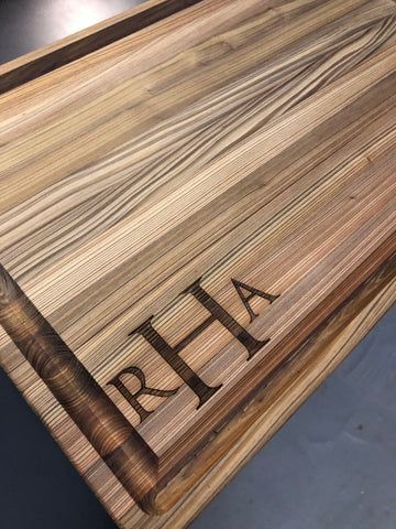 Close-up of a striped wood grain surface with the letters 'RHA' engraved near the corner