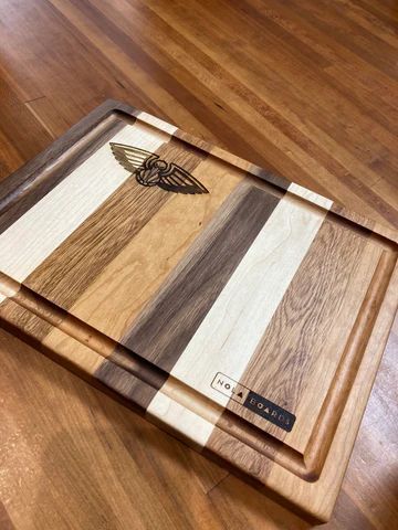 Wooden cutting board with striped light and dark wood on a wood floor