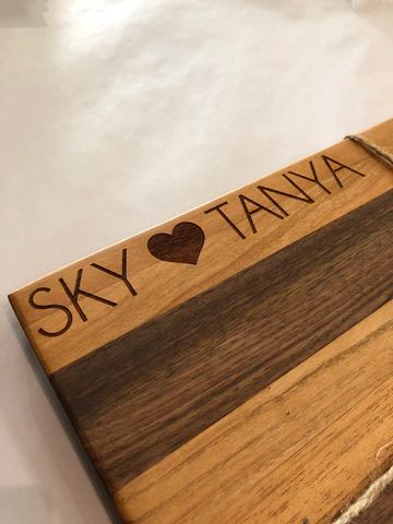 Wooden plaque engraved 'SKY ♥ TANYA' with a dark stripe on a light wood background