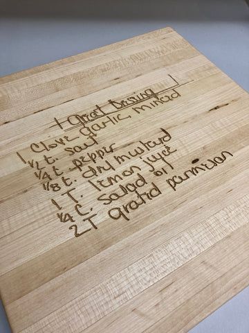 Wooden cheese board with handwritten names and places in dark marker