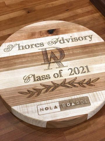 Round wooden plaque engraved 'Shores Advisory, Class of 2021' on a hardwood floor.
