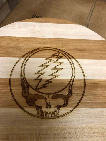 Wooden board engraved with a Grateful Dead skull and lightning bolt logo.
