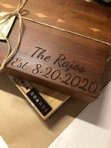 Wooden box engraved 'The Rojas Est. 8-20-2020' with a twine bow on a tan surface.