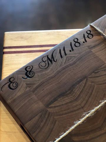 Two wooden cutting boards with engraved script and a date, stacked diagonally on a table