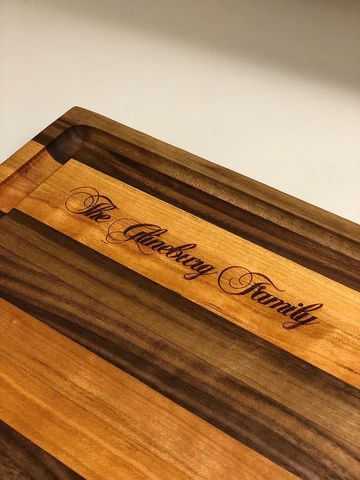 Engraved wooden cutting board with the words 'The Catering Family' and a small logo