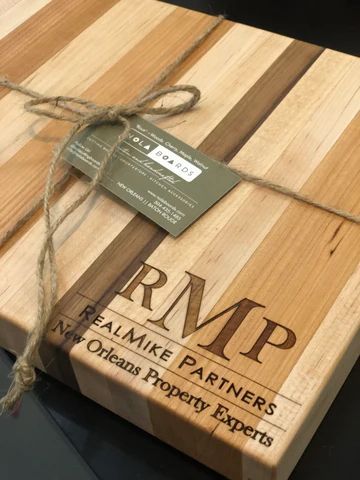 Wooden board with engraved RMP Realmk Partners logo and a tied green tag on top
