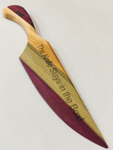 Decorative wooden boomerang with red and yellow stripes and engraved text on a white background