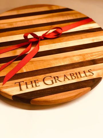 Round wooden board with red ribbon and engraved text 'THE GRABILS'