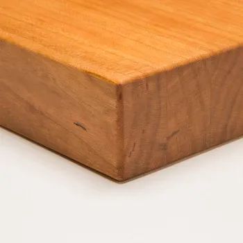 Close-up of the corner of a smooth, warm-toned cherry wood block resting on a white surface.
