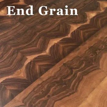 Close-up view of wood grain on a butcher block, featuring a chevron pattern of light and dark brown tones.