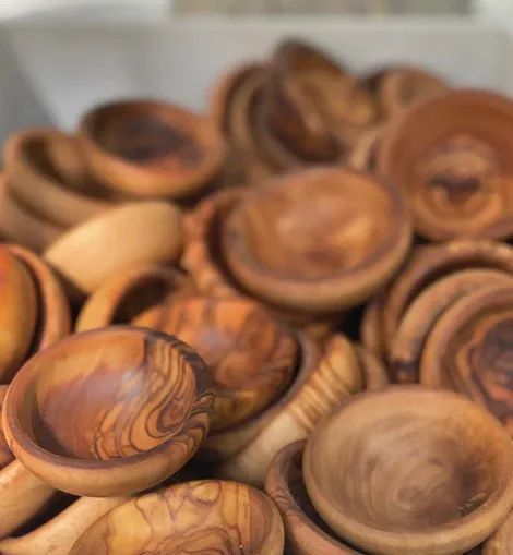 A pile of small, rustic wooden bowls featuring prominent, swirling natural wood grain patterns.