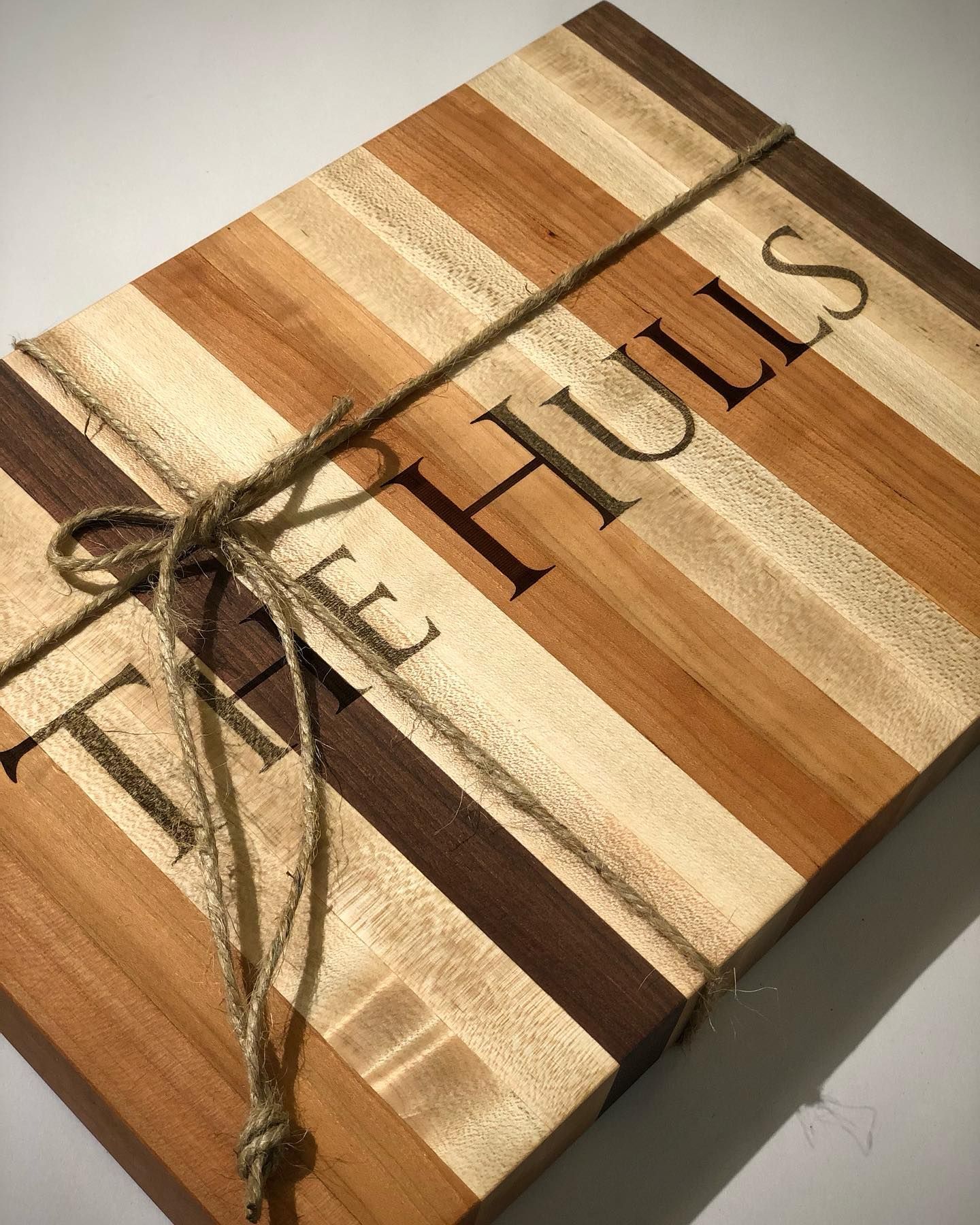 A striped wooden cutting board with a rustic twine bow.