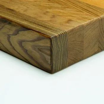 A close-up view of a thick, finished wood block showcasing vertical and horizontal wood grain patterns.