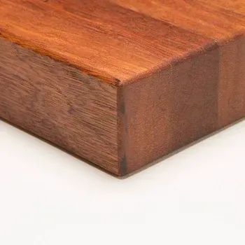 A close-up view of the corner of a thick, reddish-brown wooden butcher block cutting board.