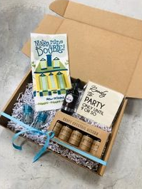Gift box with party snacks, drinks, and blue ribbon packaging on a table