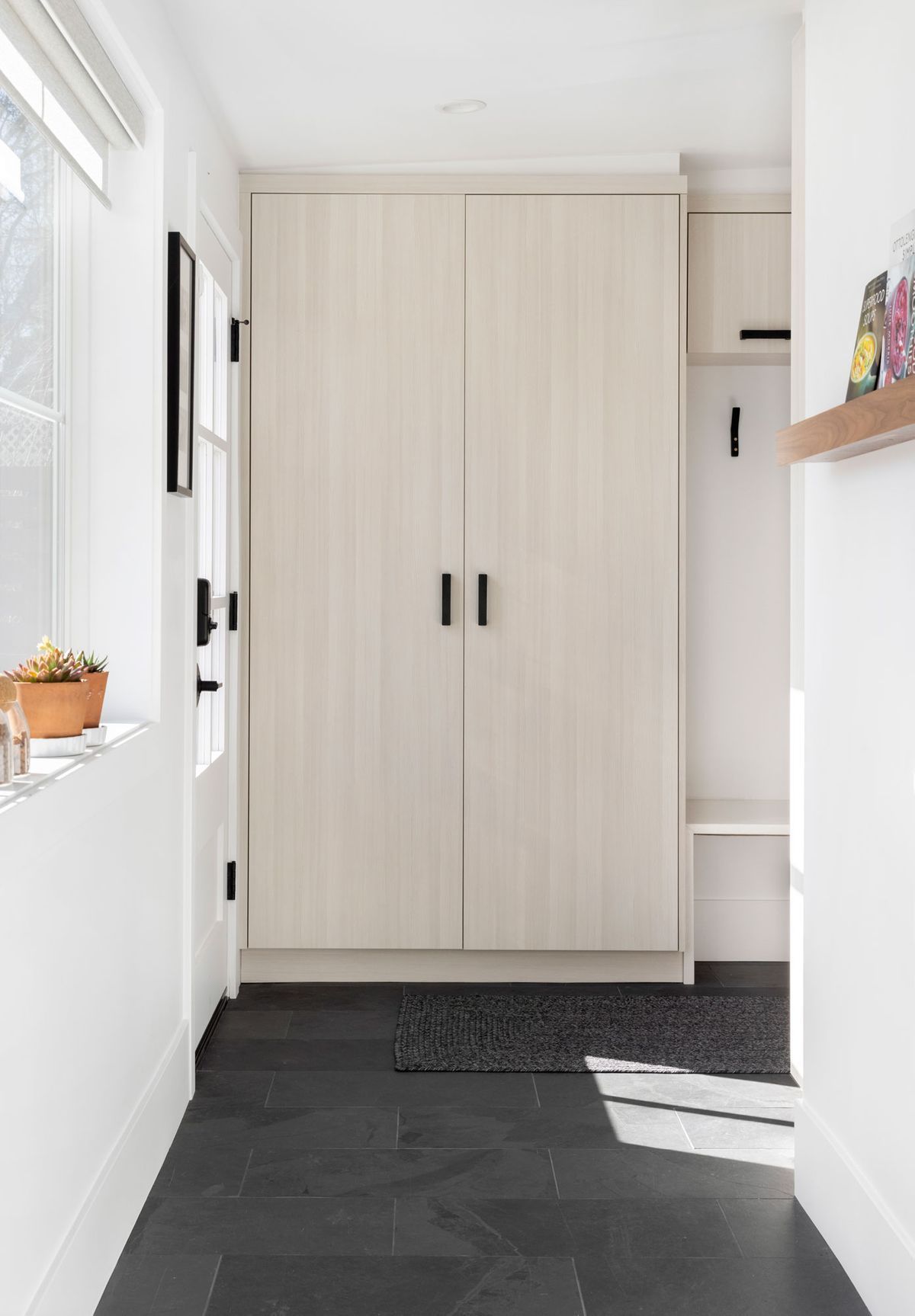 A hallway with white cabinets and a black floor.