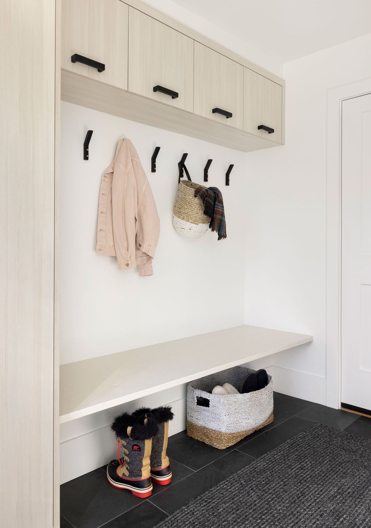 A mud room with a bench, hooks, and a basket.