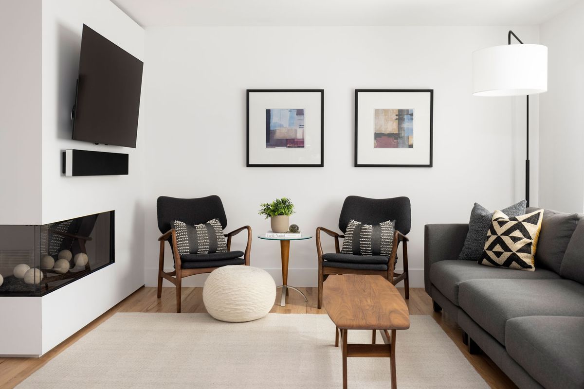 A living room with a couch, two chairs, a coffee table, and a flat screen tv.