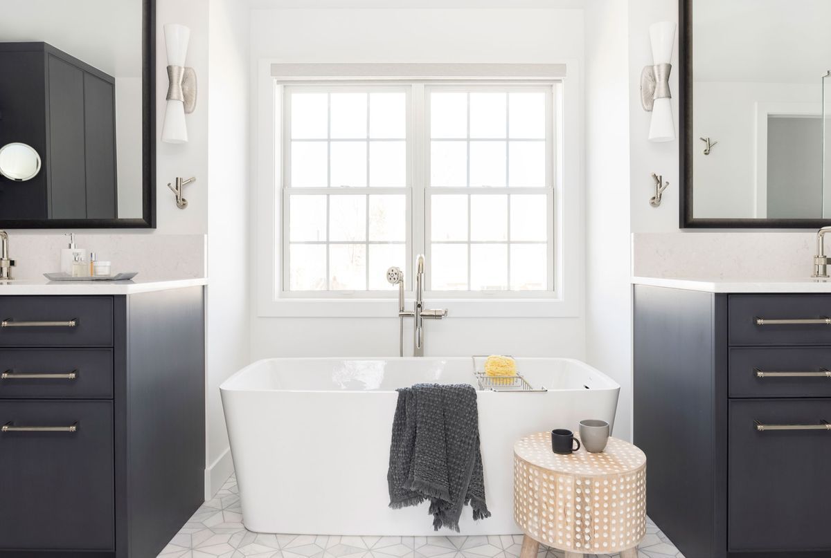 A bathroom with two sinks, a tub, and a window.