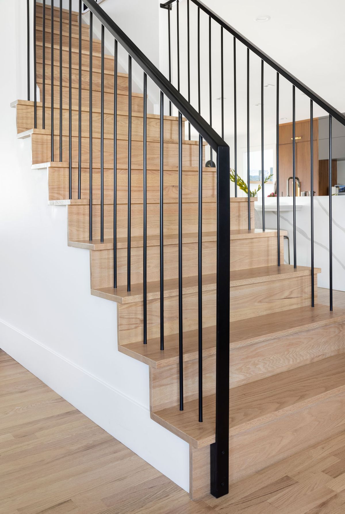 A hallway with hardwood floors, a rug, a mirror, and a bench.