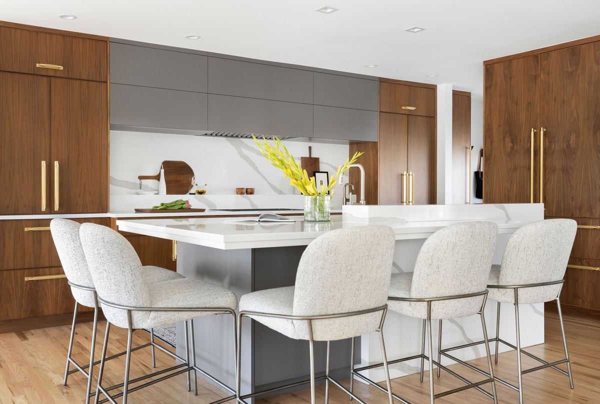 A kitchen with a large island and white chairs.