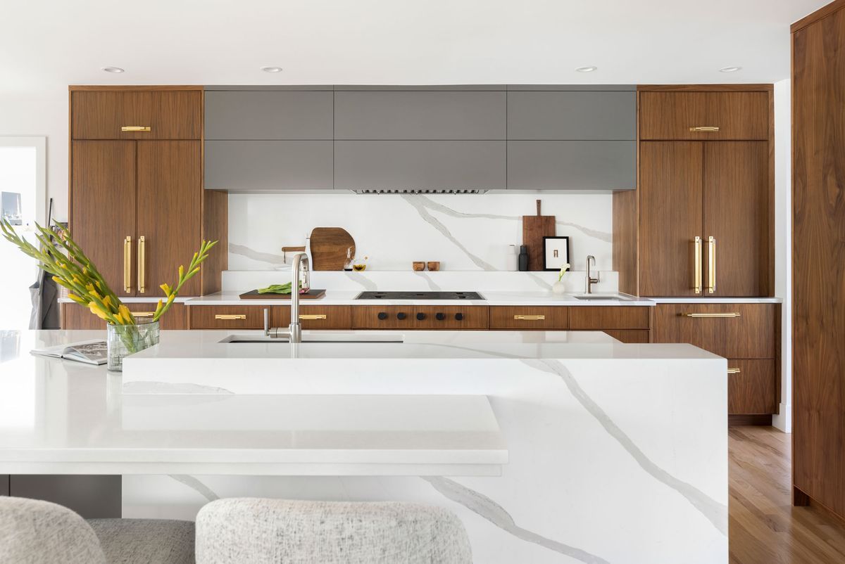 A kitchen with wooden cabinets, white counter tops, and a large island.