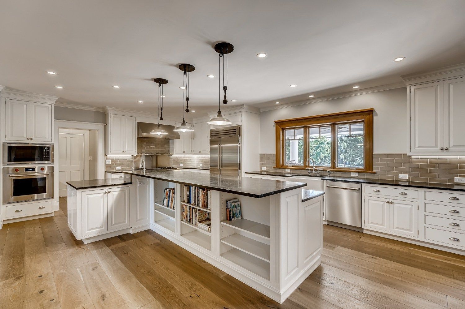A large kitchen with white cabinets and stainless steel appliances and a large island.