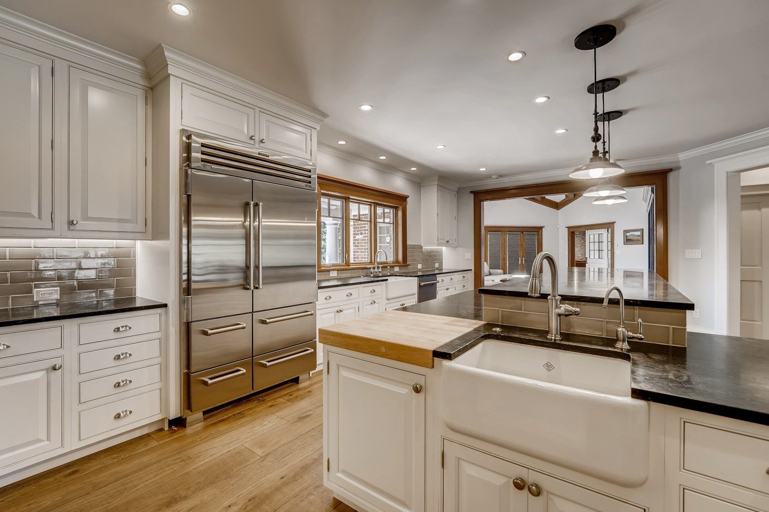 A large kitchen with white cabinets, stainless steel appliances, and hardwood floors.