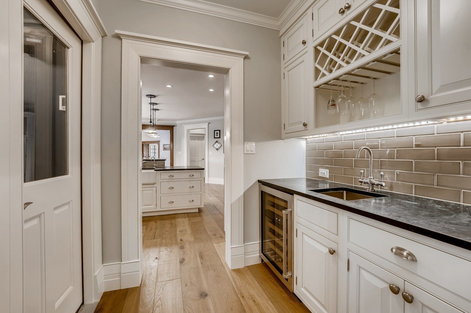 A kitchen with white cabinets, granite counter tops, and a wine rack.